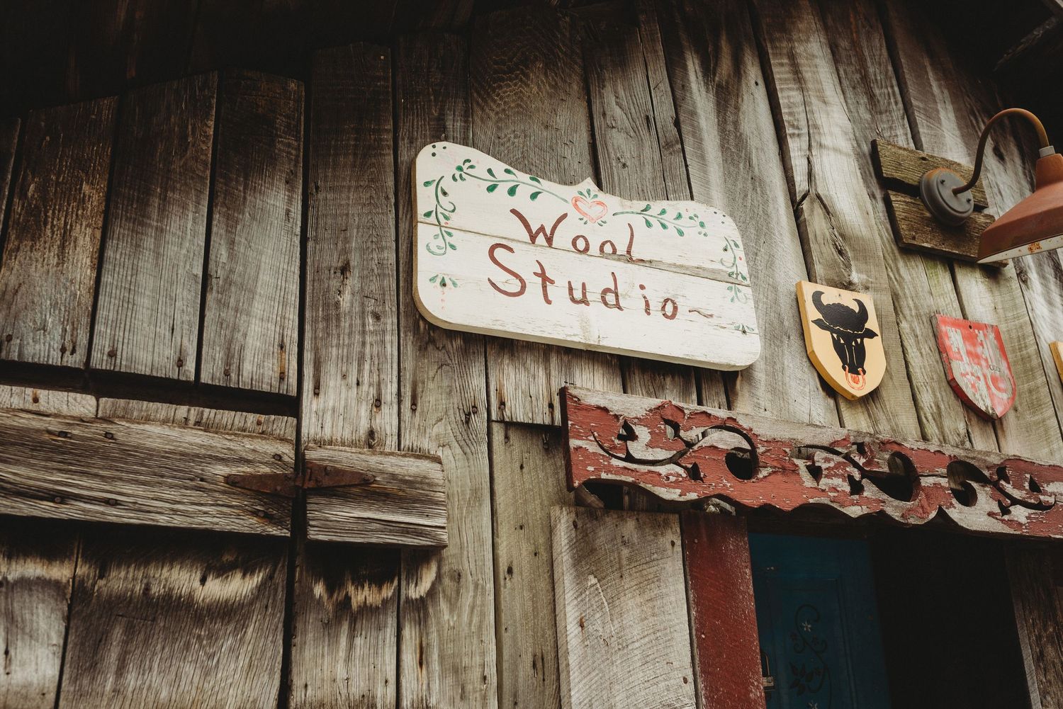 Weathered wooden sign reading 'Wood Studio' mounted on rustic barn wall.