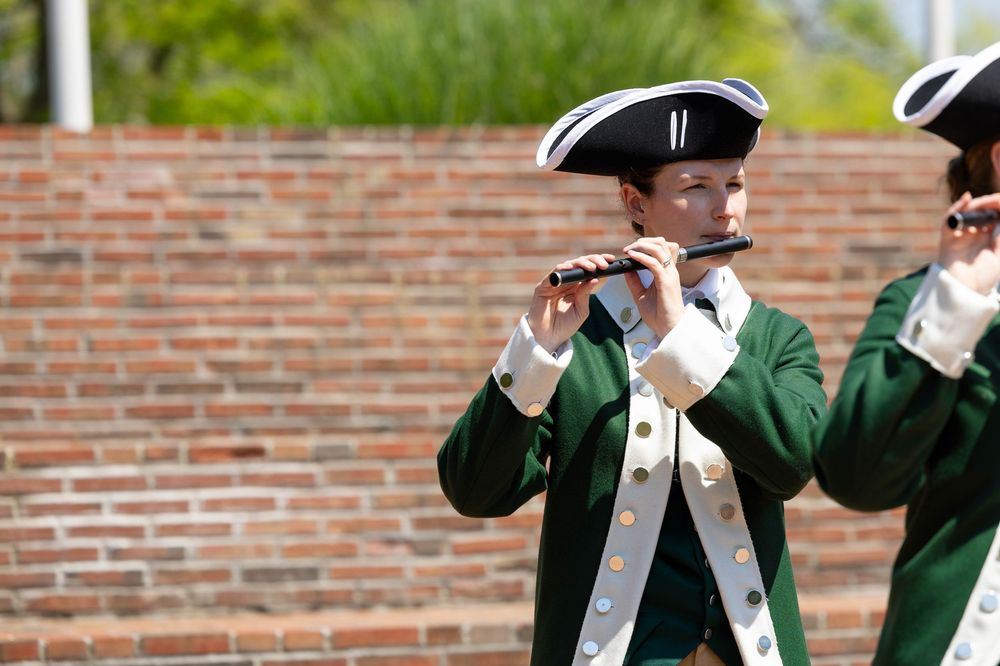 Fife and drum musicians in Revolutionary War-era costumes performing at a muster