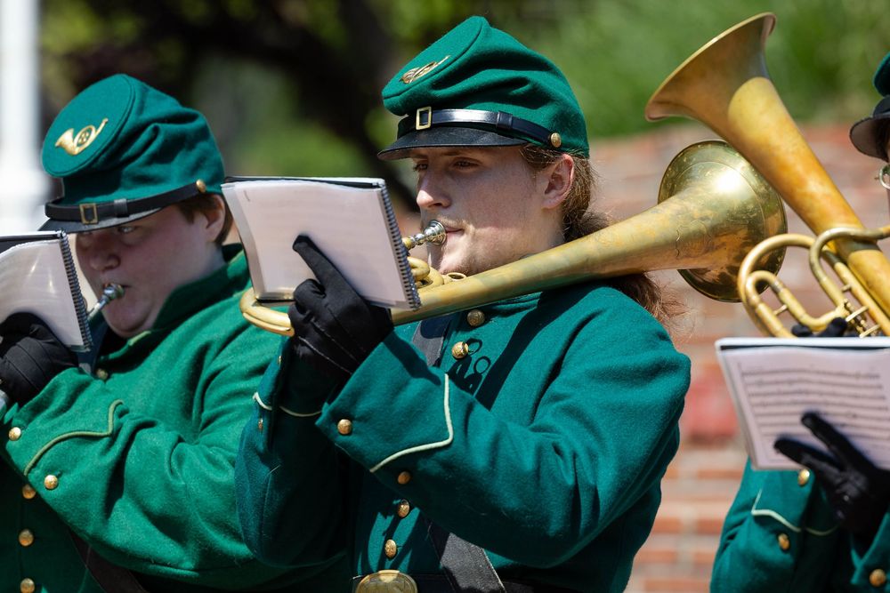 Green Machine brass musician in green uniform performing outdoors during an event.