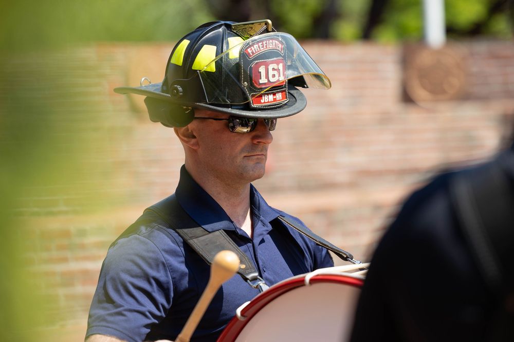 Bass drummer wearing a firefighter helmet at a muster