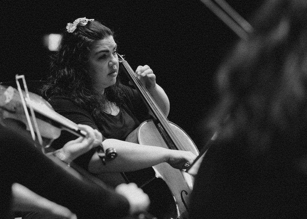 Black and white close-up of a cellist performing passionately during a live symphony orchestra concert.