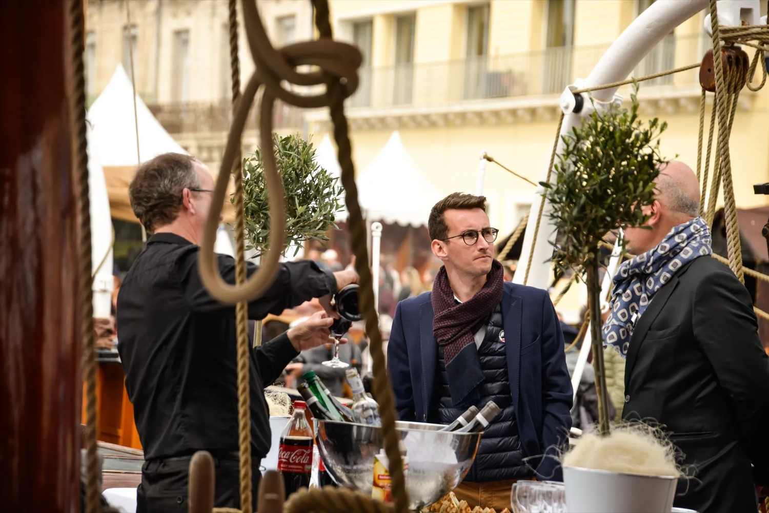 Deux hommes en discussion lors d’un événement en plein air, entourés de participants dans une ambiance conviviale.