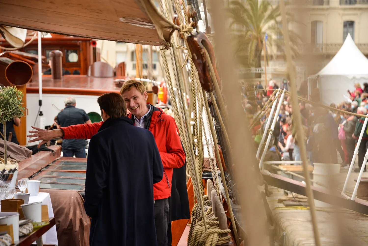 Deux femmes échangent en extérieur, à bord d’un bateau amarré, avec une ambiance chaleureuse et marine.