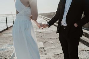 Groom helping bride with her dress on the rocks – candid moment