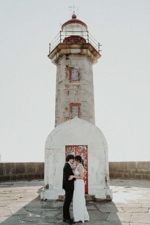 Wide cinematic frame of couple walking away from the lighthouse