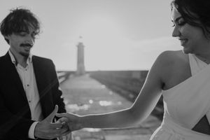A black and white film wedding photo of a couple during their elopement in Portugal with a lighthouse in the background.