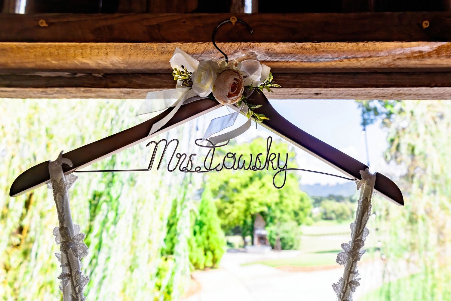 Custom wooden wedding dress hanger with 'Mrs. Lewicky' text and floral decorations.