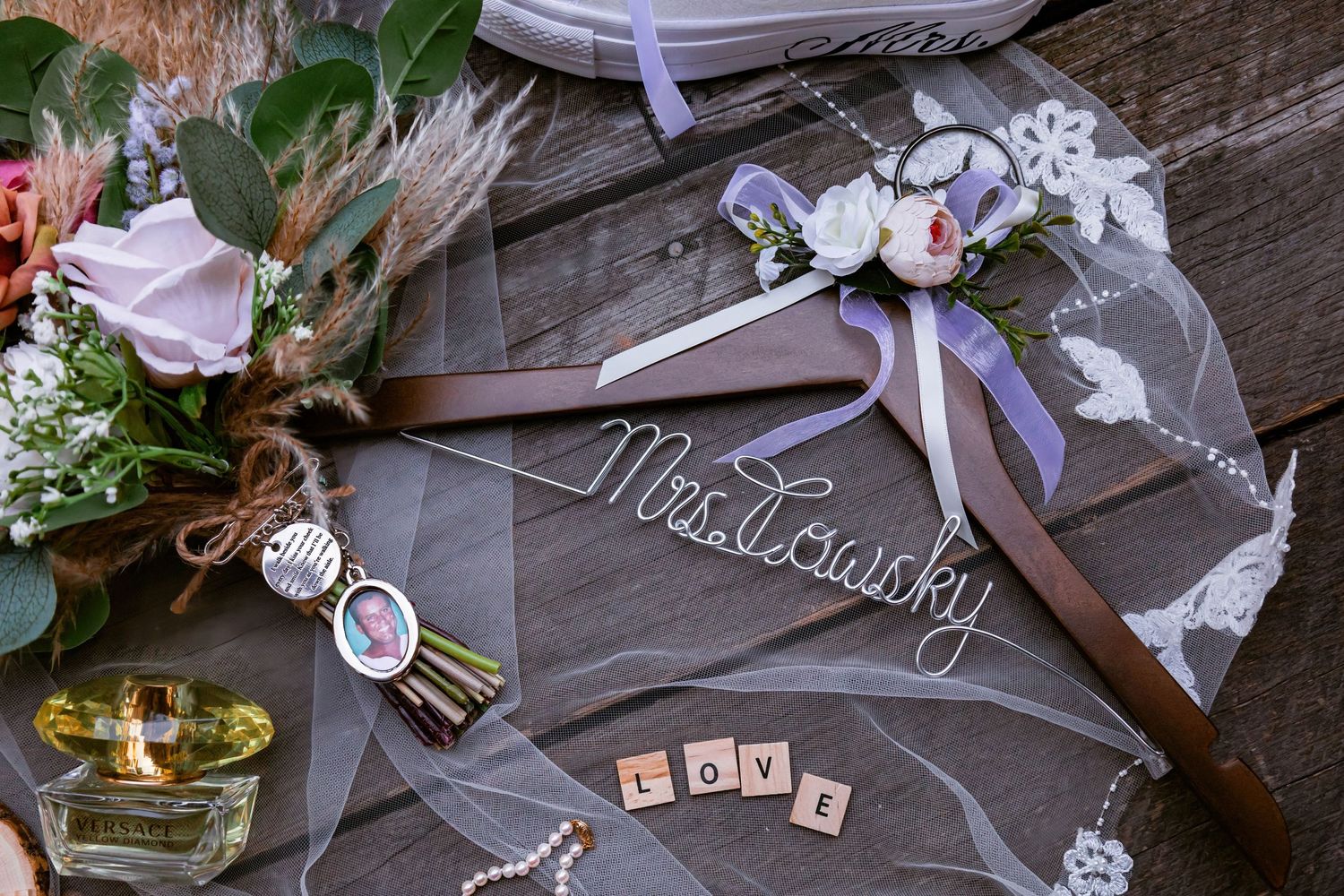 Personalized wedding hangers with floral decorations and 'Mrs Lewicky' text on wooden background.