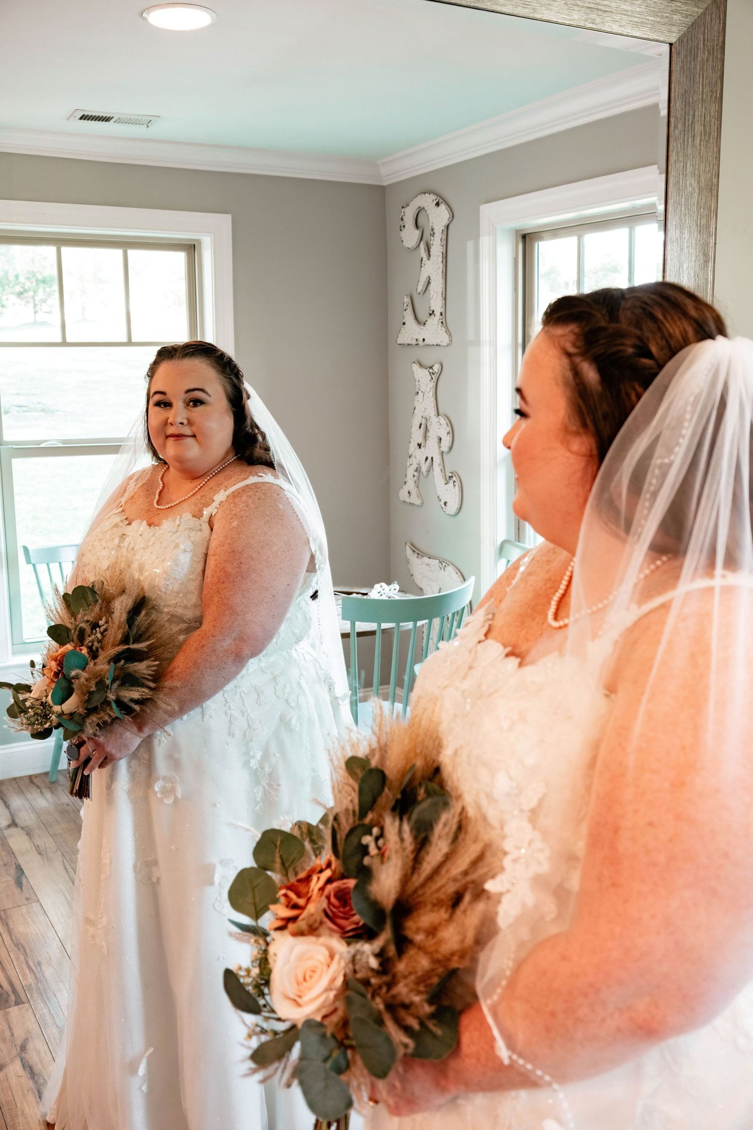 Person in wedding dress looking at reflection in bright modern room.