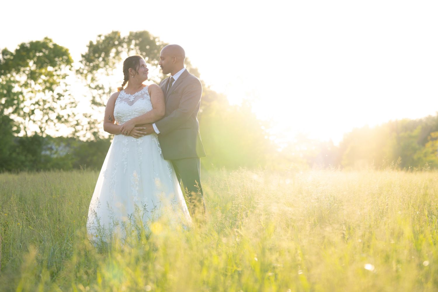 Romantic sunset wedding photos taken in a golden meadow with soft natural lighting.