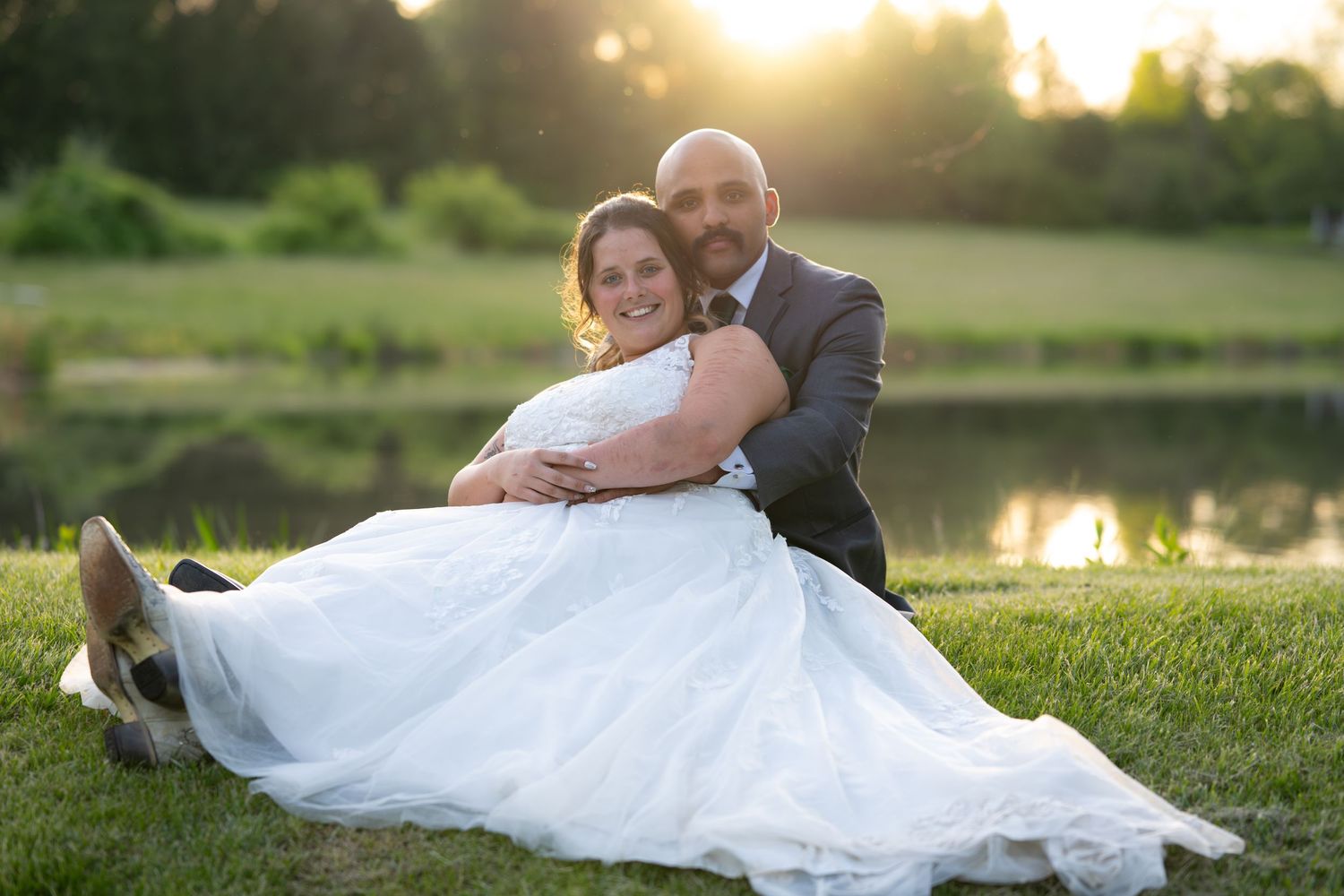 Sunset wedding photos captured on grassy hillside near a lake.