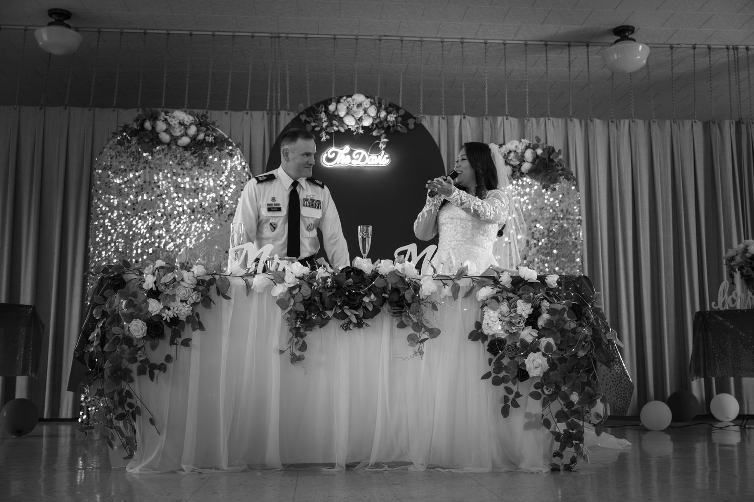 Wedding reception venue decorated with floral arrangements and white drapery.
