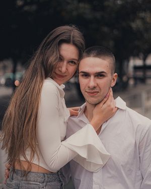 Couple in white outfits posing together outdoors.