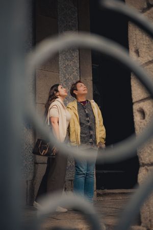 Two people looking up through circular window frame.