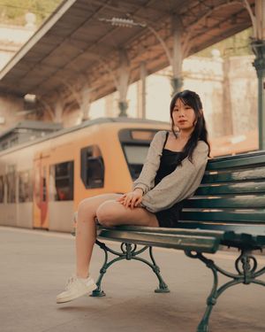 Person sitting on green bench at train platform.