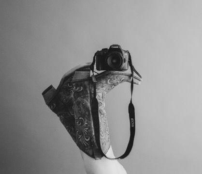 Black and white studio picture, branding session, cowboy boots and camera, western vibes.