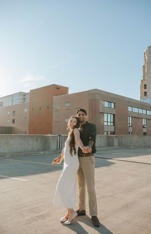 A couple dances and laughs together on an empty rooftop parking area.