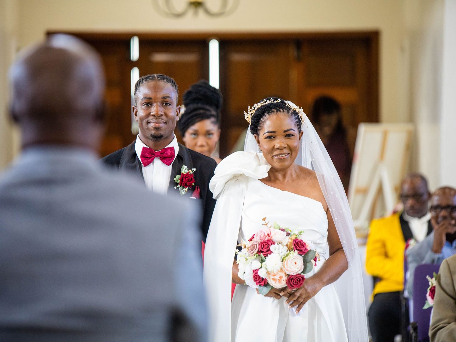 A beautiful wedding ceremony captured at the altar with a bride in white holding a pink and white bouquet.