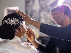 A hairstylist adjusts a sparkly hair accessory during a wedding preparation session.
