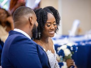 A happy couple shares a joyful moment at their wedding reception with navy blue and white decor in the background.
