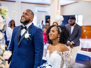 Happy couple sharing a joyful moment during their wedding ceremony in a bright indoor venue.