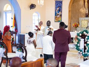 A wedding celebration takes place in a chapel adorned with arched windows and floral decorations.
