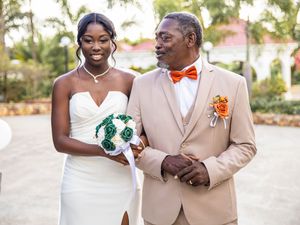 Close up of couple in wedding attire, bride in white dress with teal bouquet and groom in beige suit with orange bow tie.