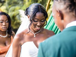 Beautiful bride in white strapless gown smiles joyfully during outdoor wedding ceremony.