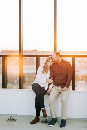 Couple leaning together against railing during golden hour sunset.
