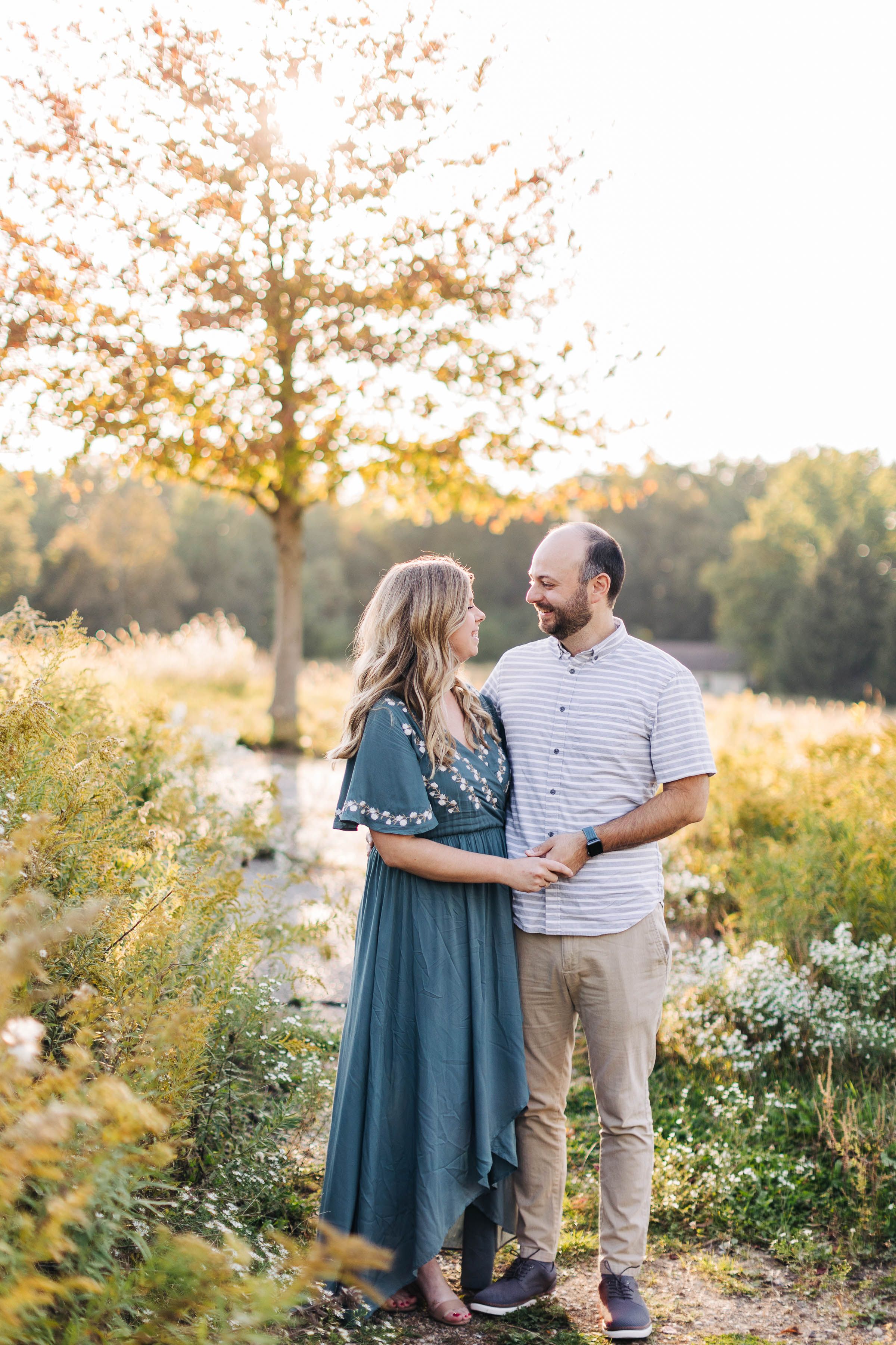 A couple sharing a romantic moment in a golden sunlit meadow during sunset.