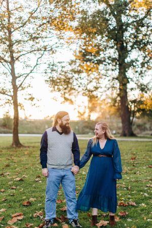 Couple holding hands in autumn park with fall foliage.