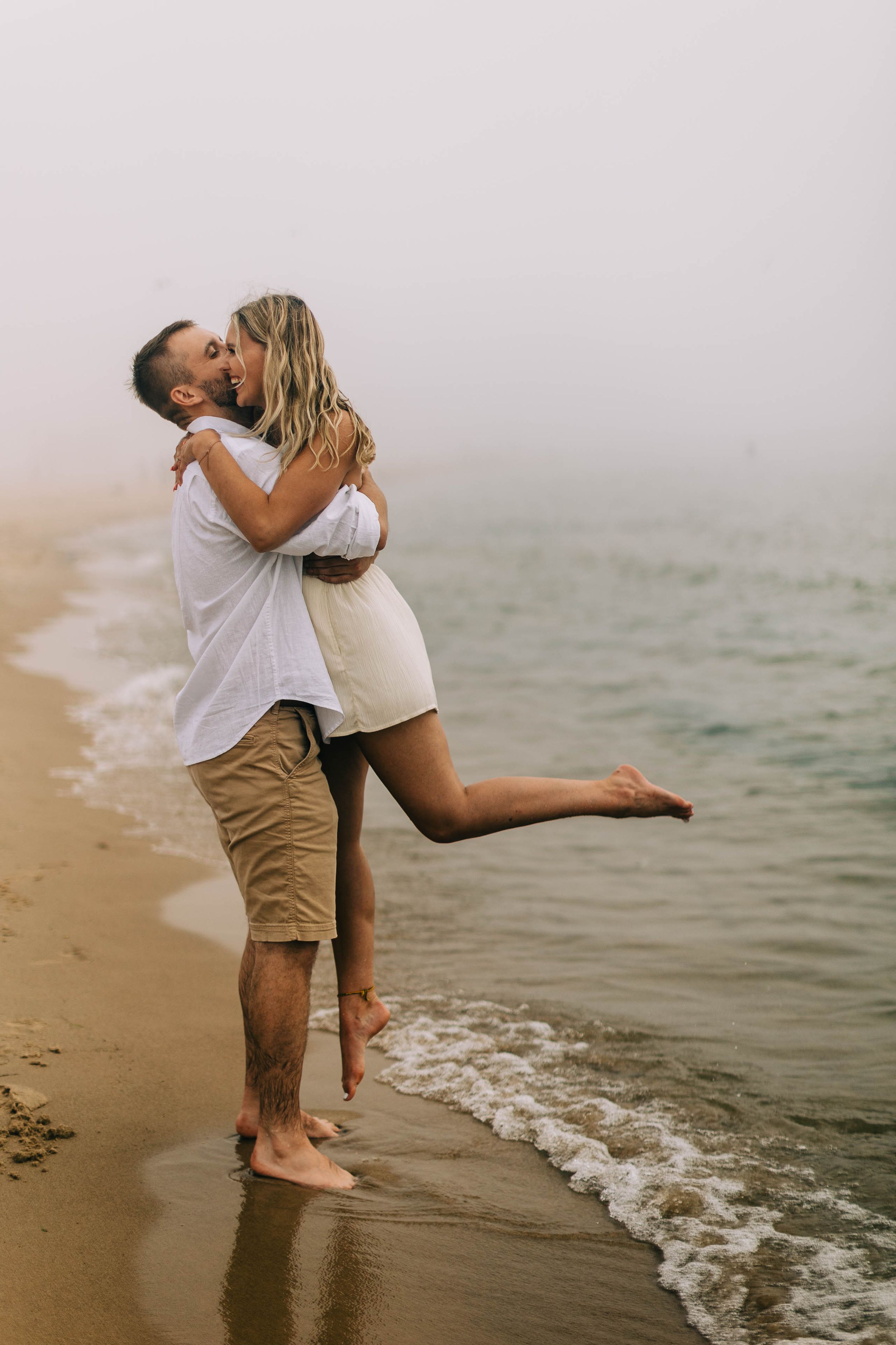Joyful couple embracing on beach at water's edge.