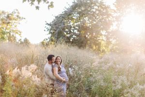 Couple embracing in sunlit wildflower meadow at golden hour.