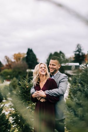 Joyful couple embracing in autumn at Christmas tree farm.