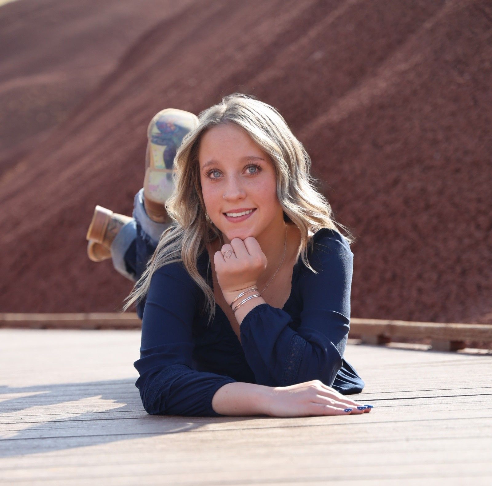 A person in a navy blue top lies on a light colored surface in a series of casual portrait poses.
