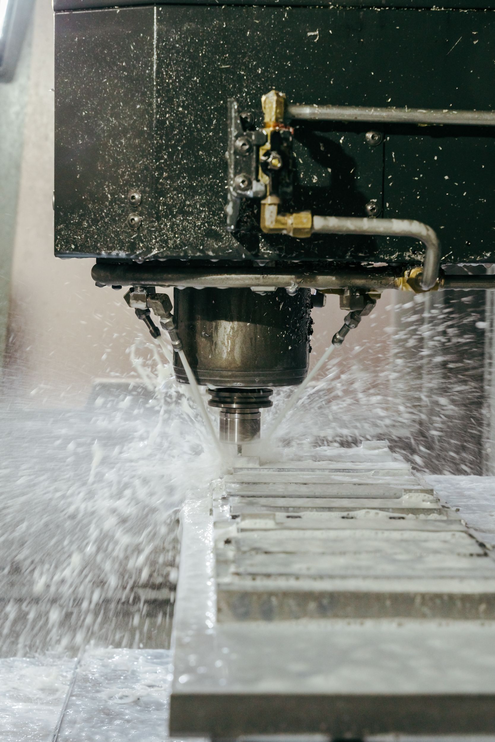 Industrial CNC machine cutting metal with coolant spray splashing during precision manufacturing process.