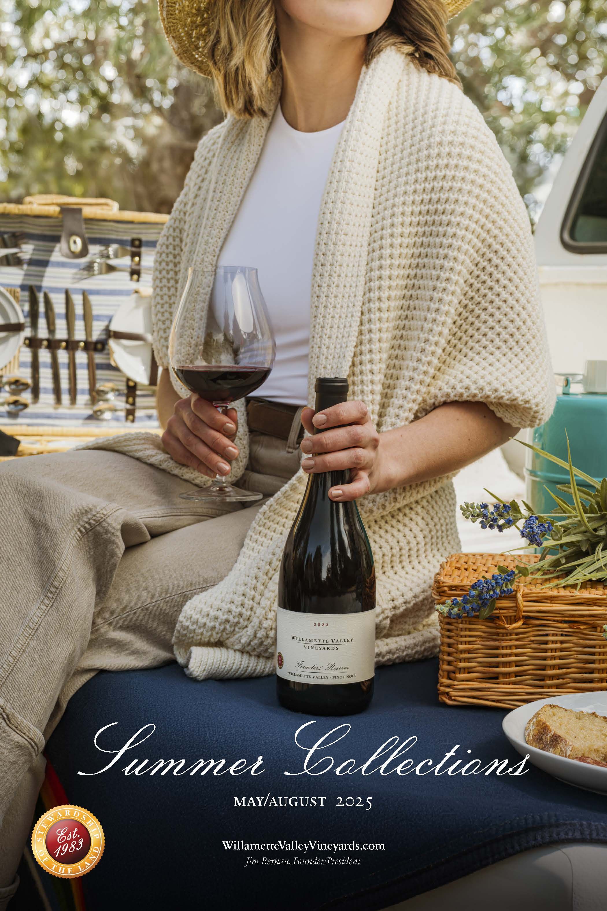 Woman in cozy knit cardigan enjoys wine during summer picnic with vintage car and wicker basket visible.