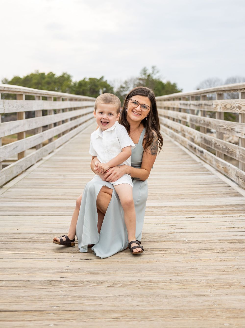 Candid lifestyle photos of a family sitting and playing together on a wooden pier.