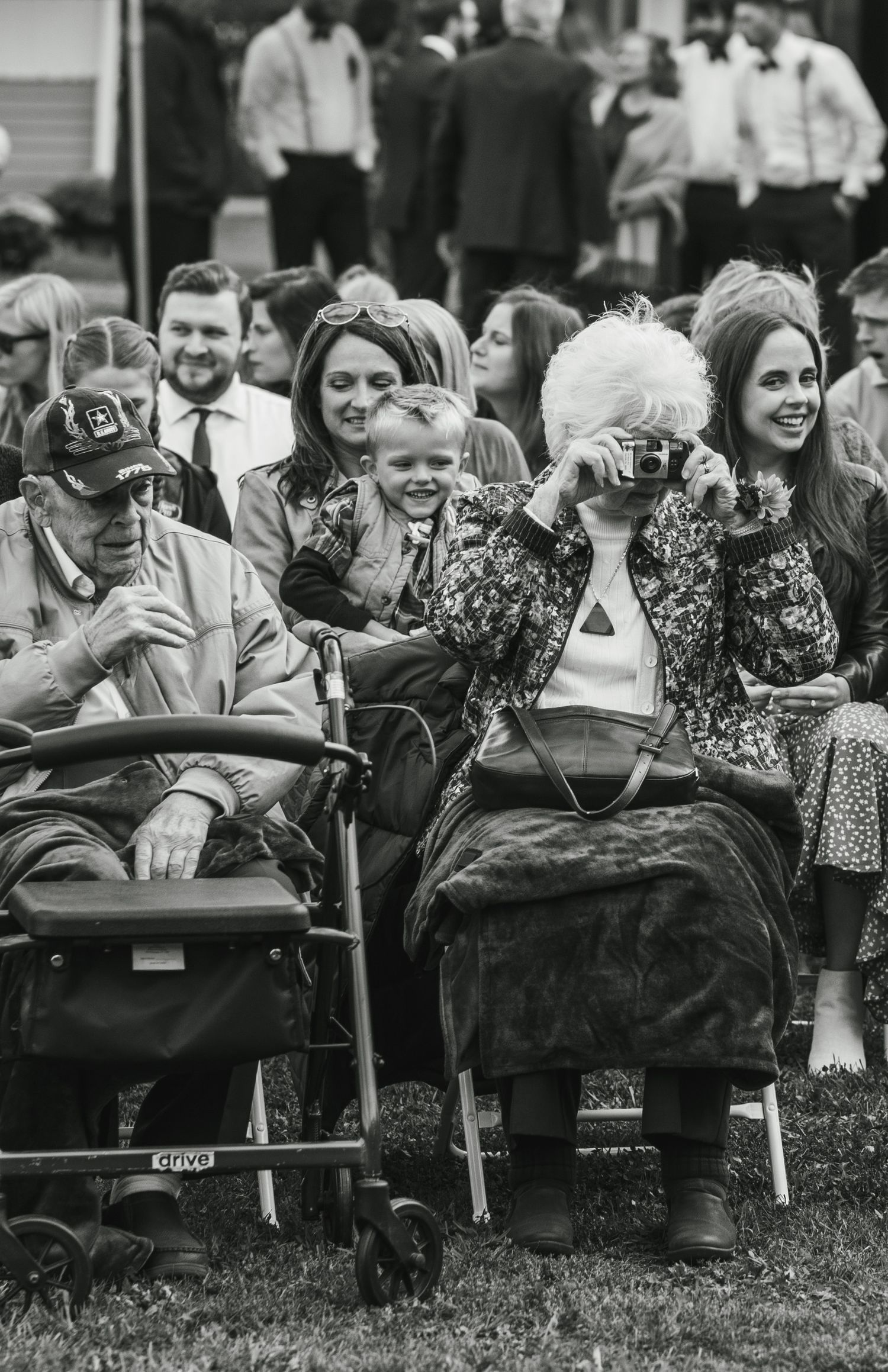A black and white photo of guests taking pictures at an outdoor event.