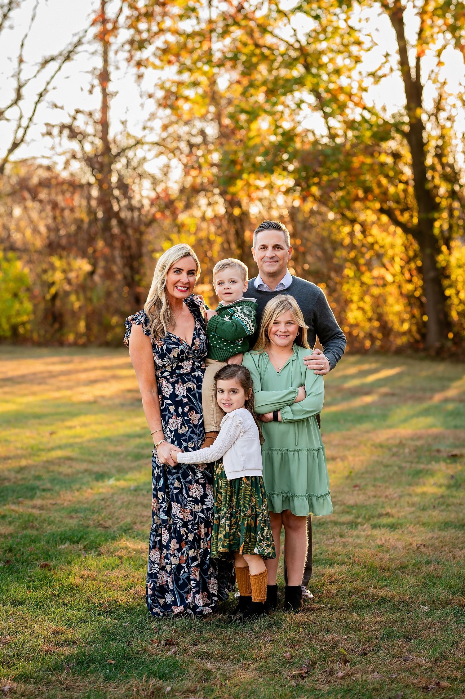 Family of five poses together during golden hour autumn photo session.