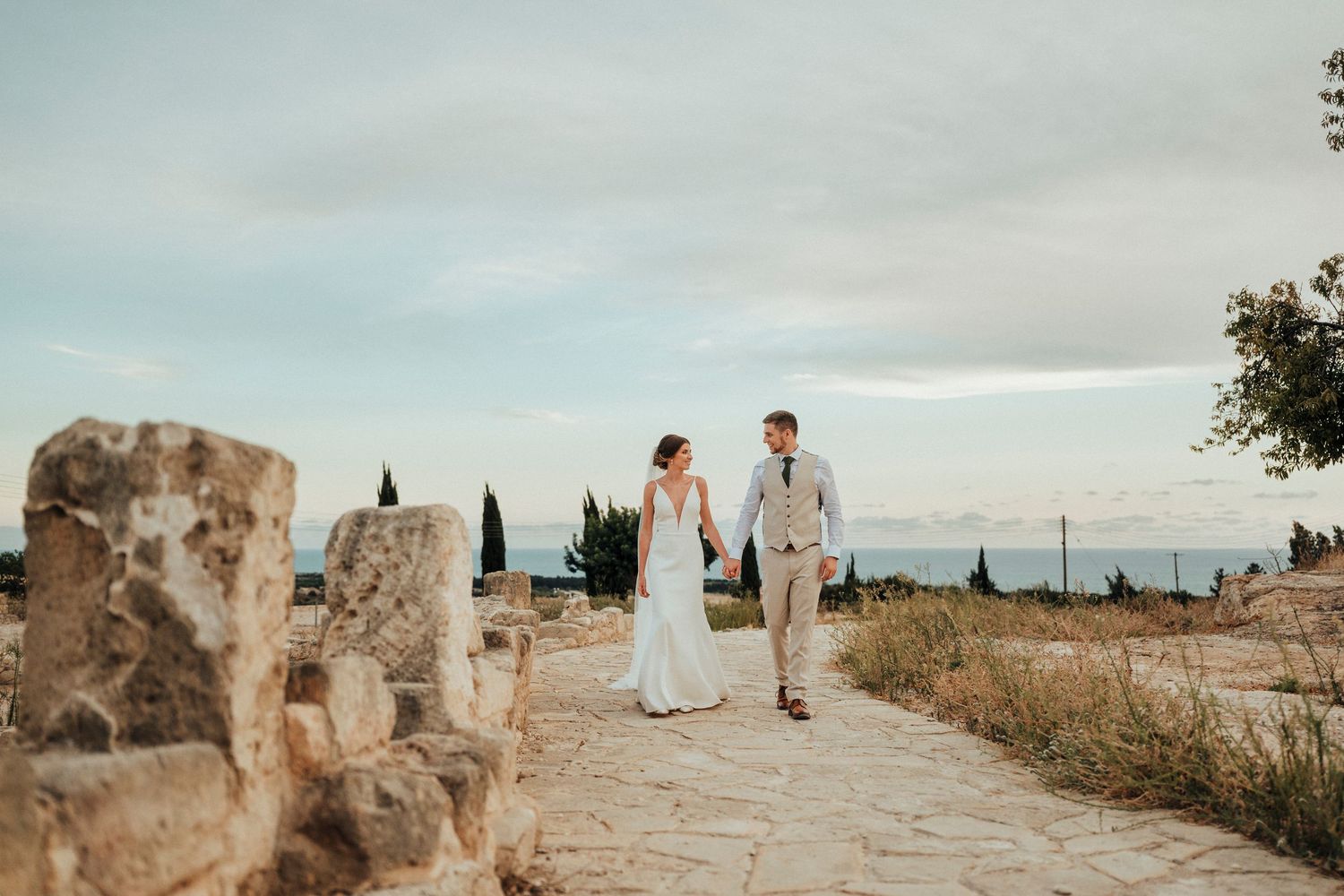 A romantic wedding moment captured among lush greenery with two people embracing in formal attire.