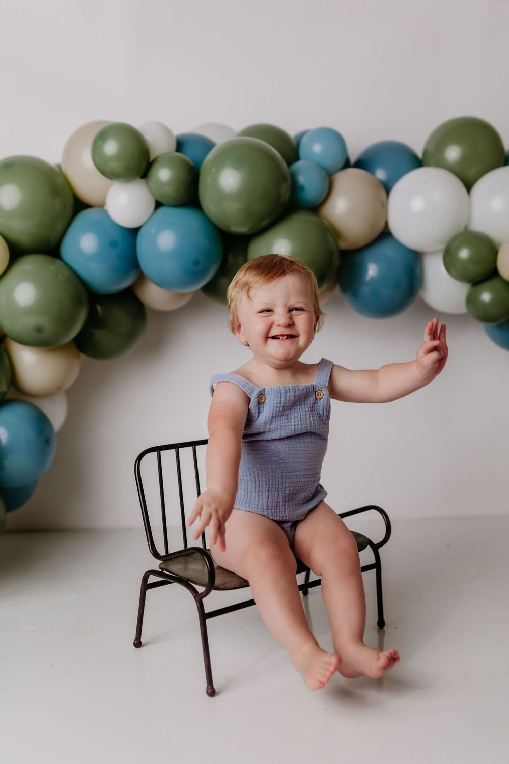 A series of photos showing a baby in a romper sitting on a small wooden chair with blue and green balloons decorating the wall.