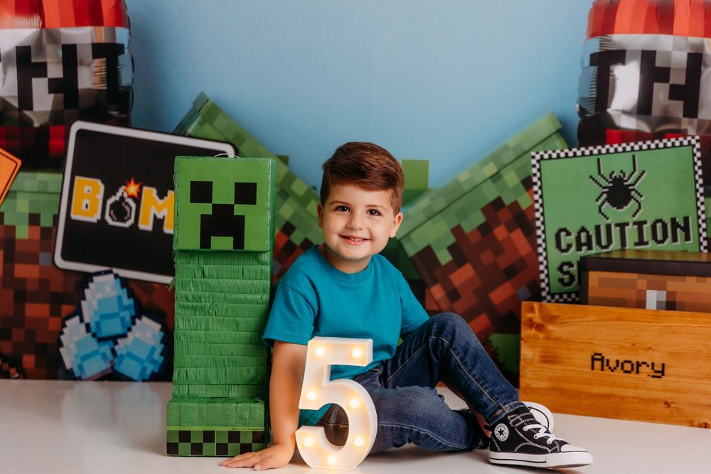 A birthday setup with Minecraft-themed decorations featuring a large wooden number 5 and pixelated block designs.