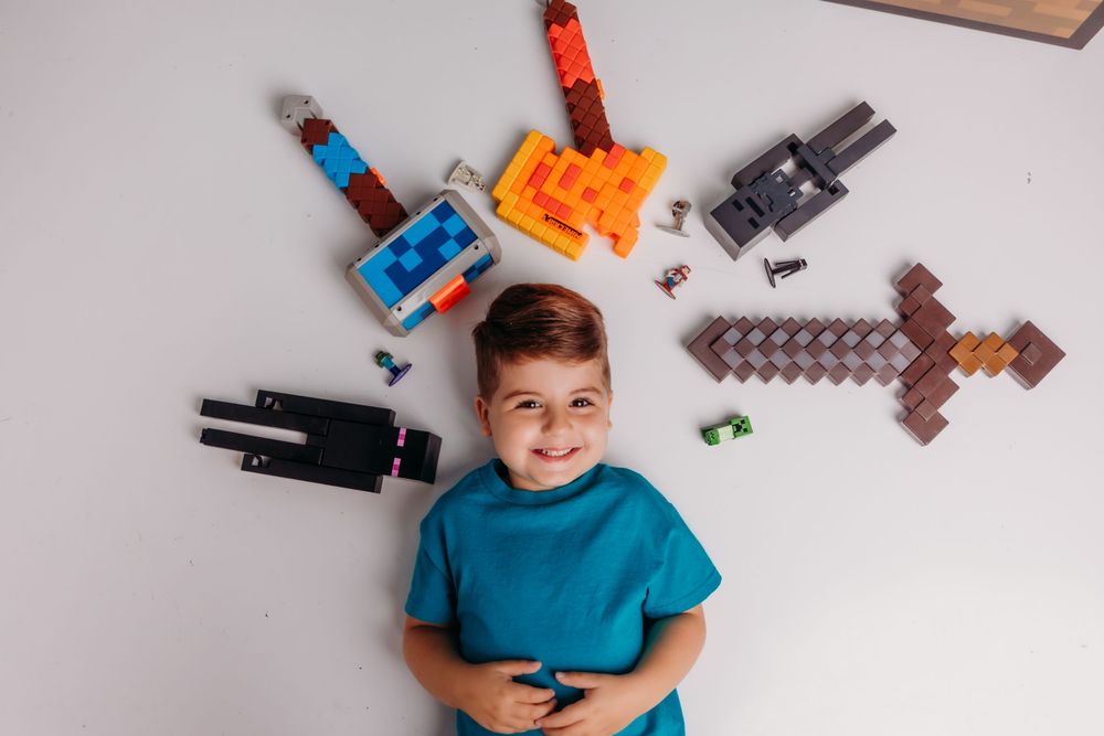 Child arranges a collection of colorful building blocks and toys while playing on the floor.