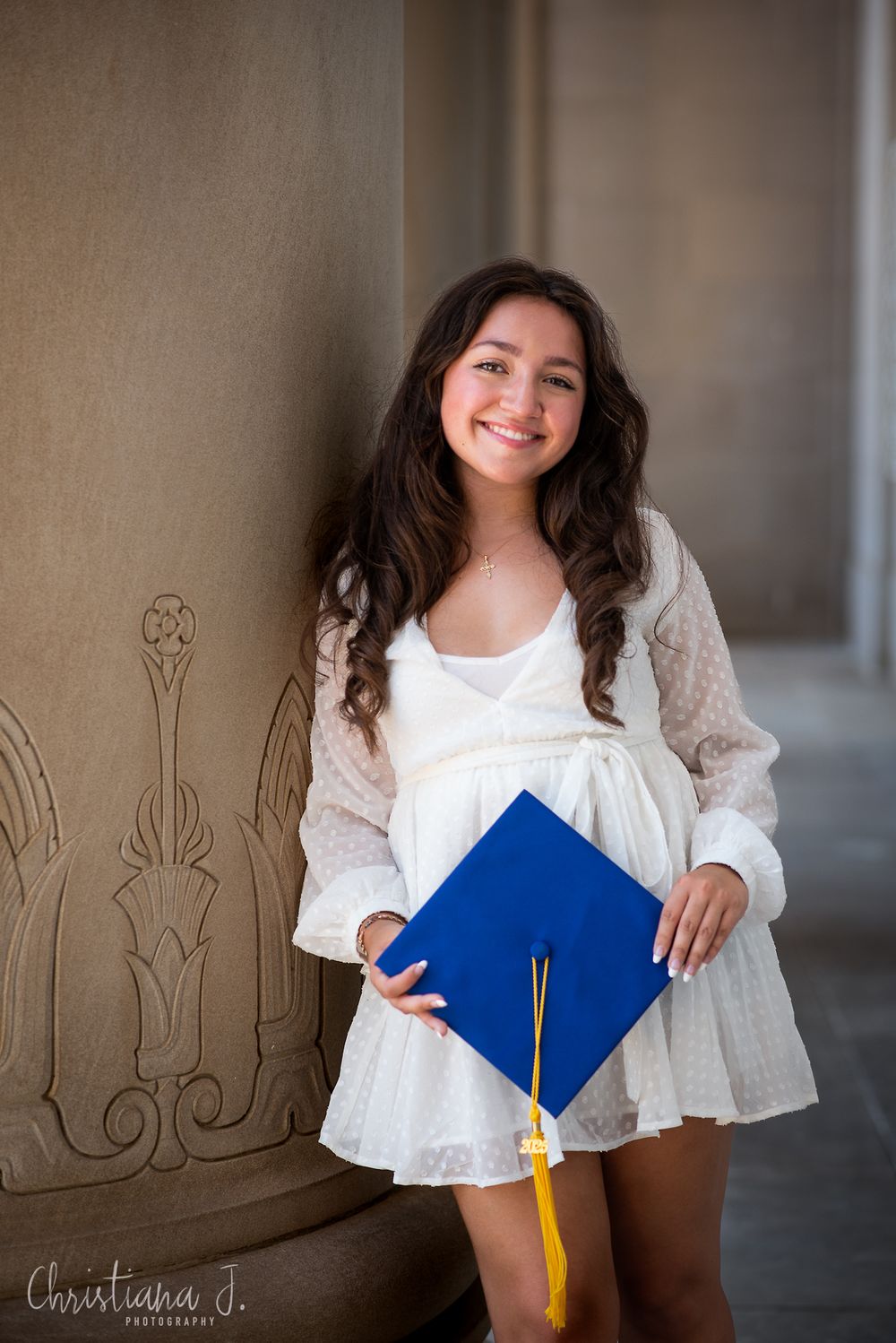 high school senior girl graduation photoshoot with blue grad cap at Nelson Atkins museum in kansas city missouri wearing white dress