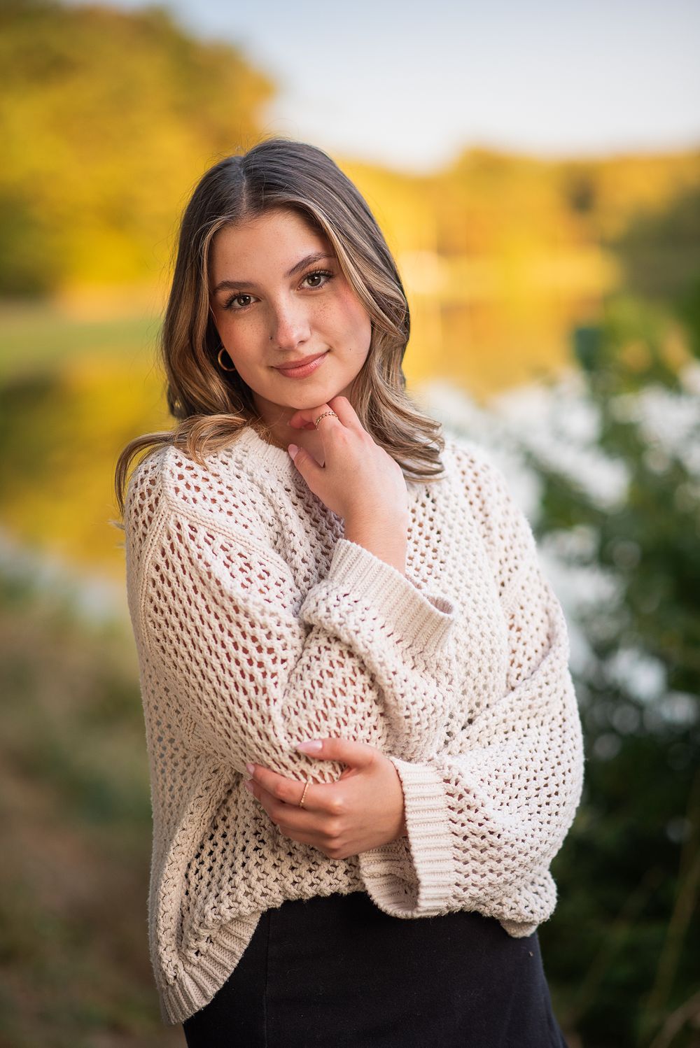 High school senior photographer Kansas City, senior girl portrait in chunky knit cream sweater with autumn foliage backdrop and soft light.