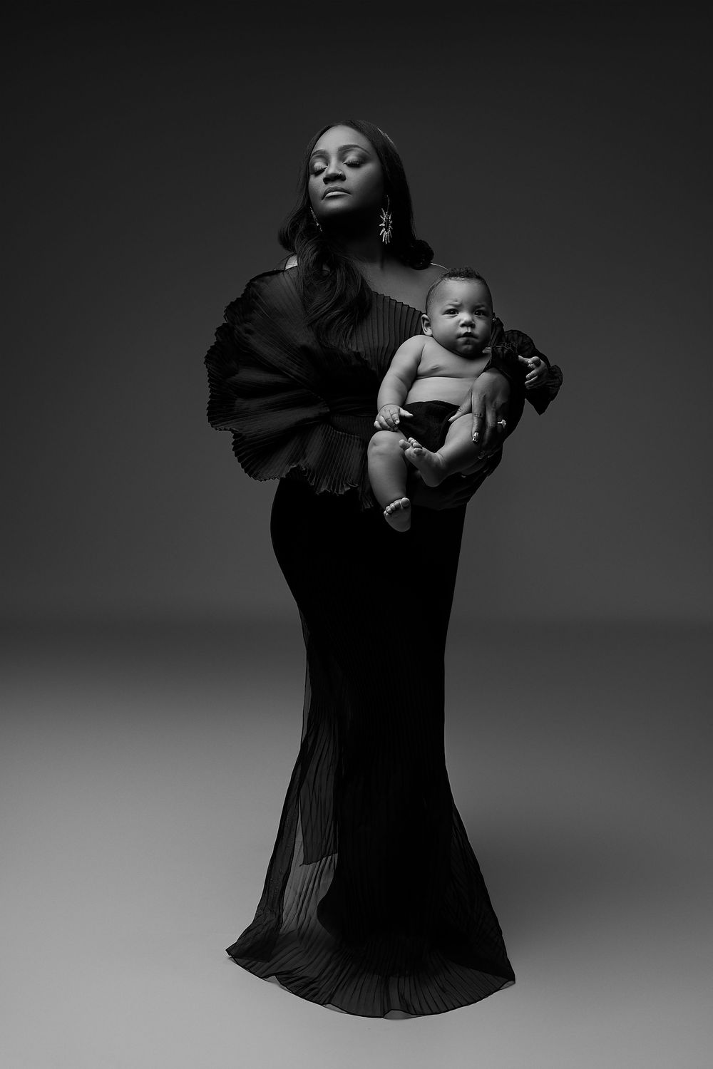 A dramatic black and white fashion series showing a figure in flowing black garments against a dark background.