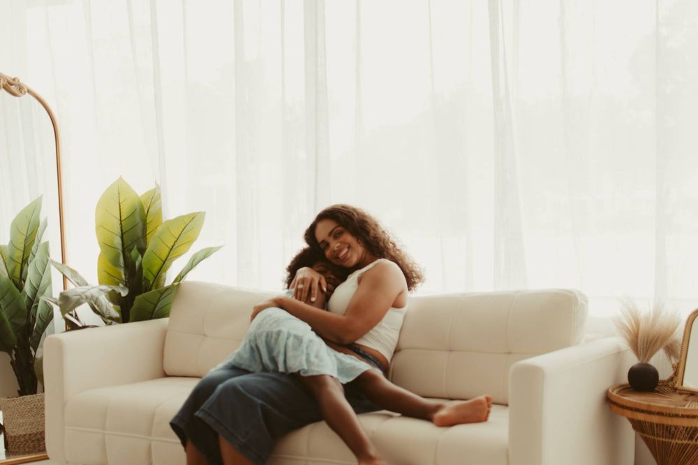 Cozy scene of people relaxing on white sofa in bright, airy room with plants.