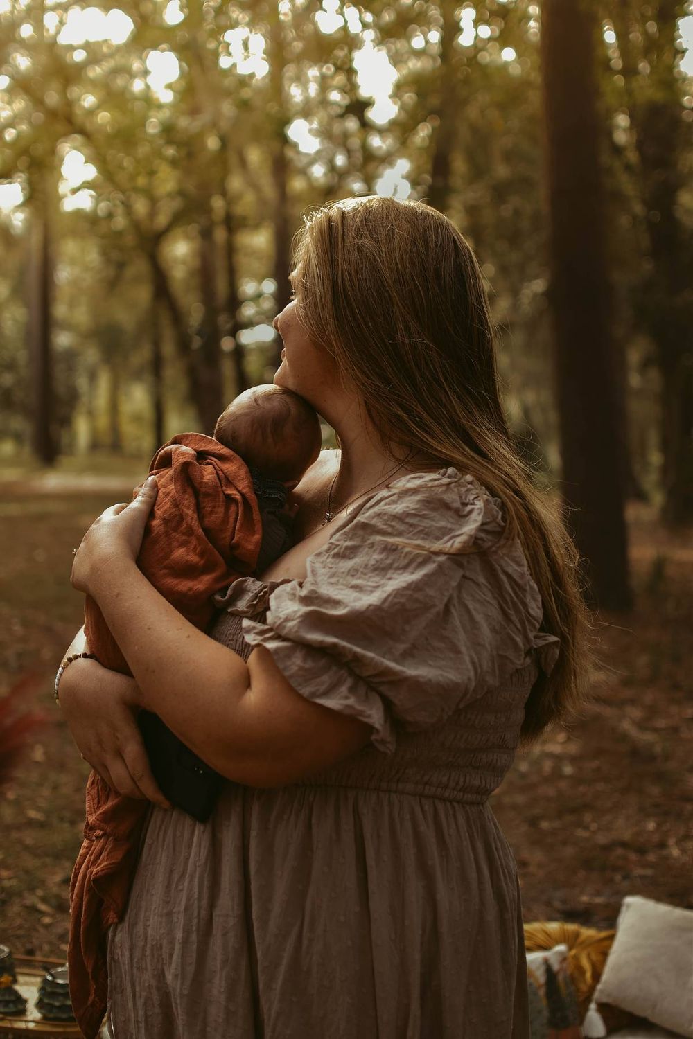 Mother and baby sharing a tender moment in a sunlit forest setting.