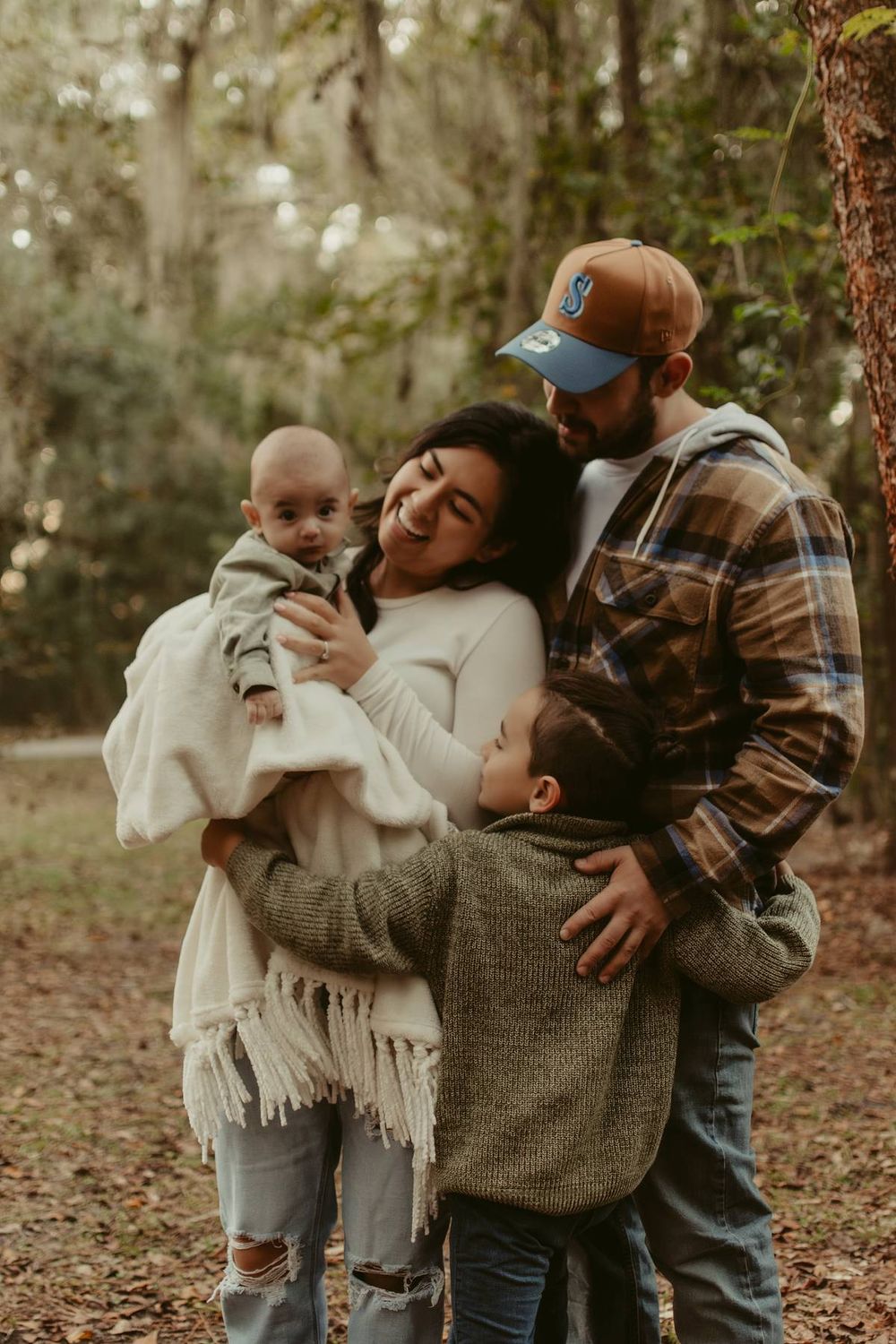 Family sharing warm embraces in a wooded area during autumn.
